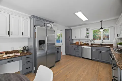 a kitchen with granite countertop a refrigerator stove and sink