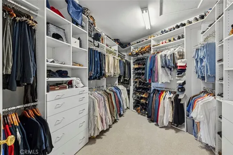 a view of walk in closet with clothes and shoes