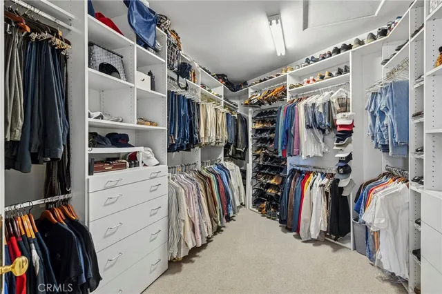 a view of walk in closet with clothes and shoes