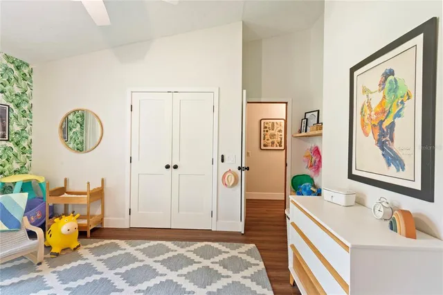 a bedroom with a bed a stove and a dining table with wooden floor