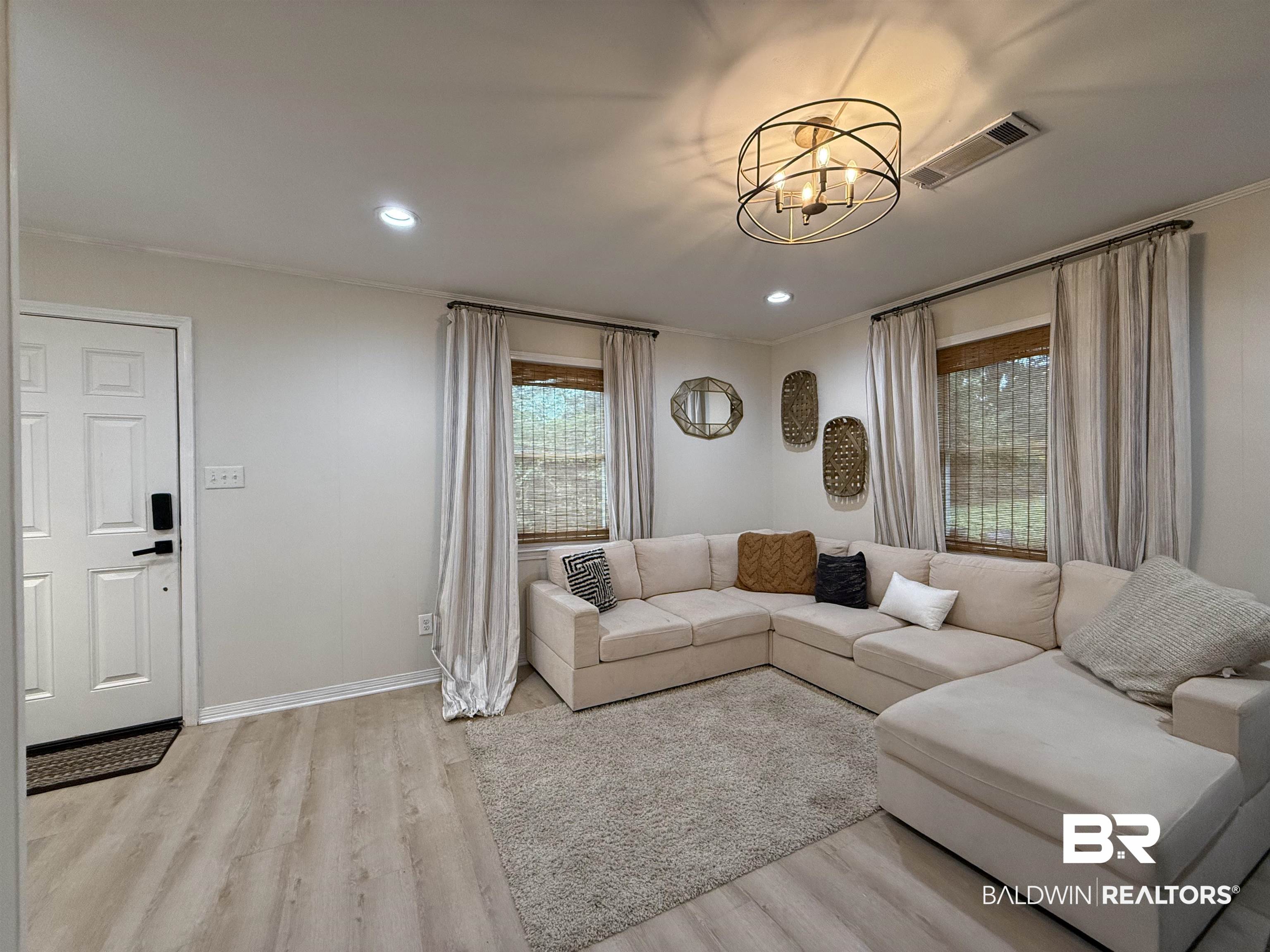 90 Florida Street Monroeville, AL 36460 - Photo 20 of 31 Living room with light hardwood / wood-style floors, crown molding, a wealth of natural light, and an inviting chandelier