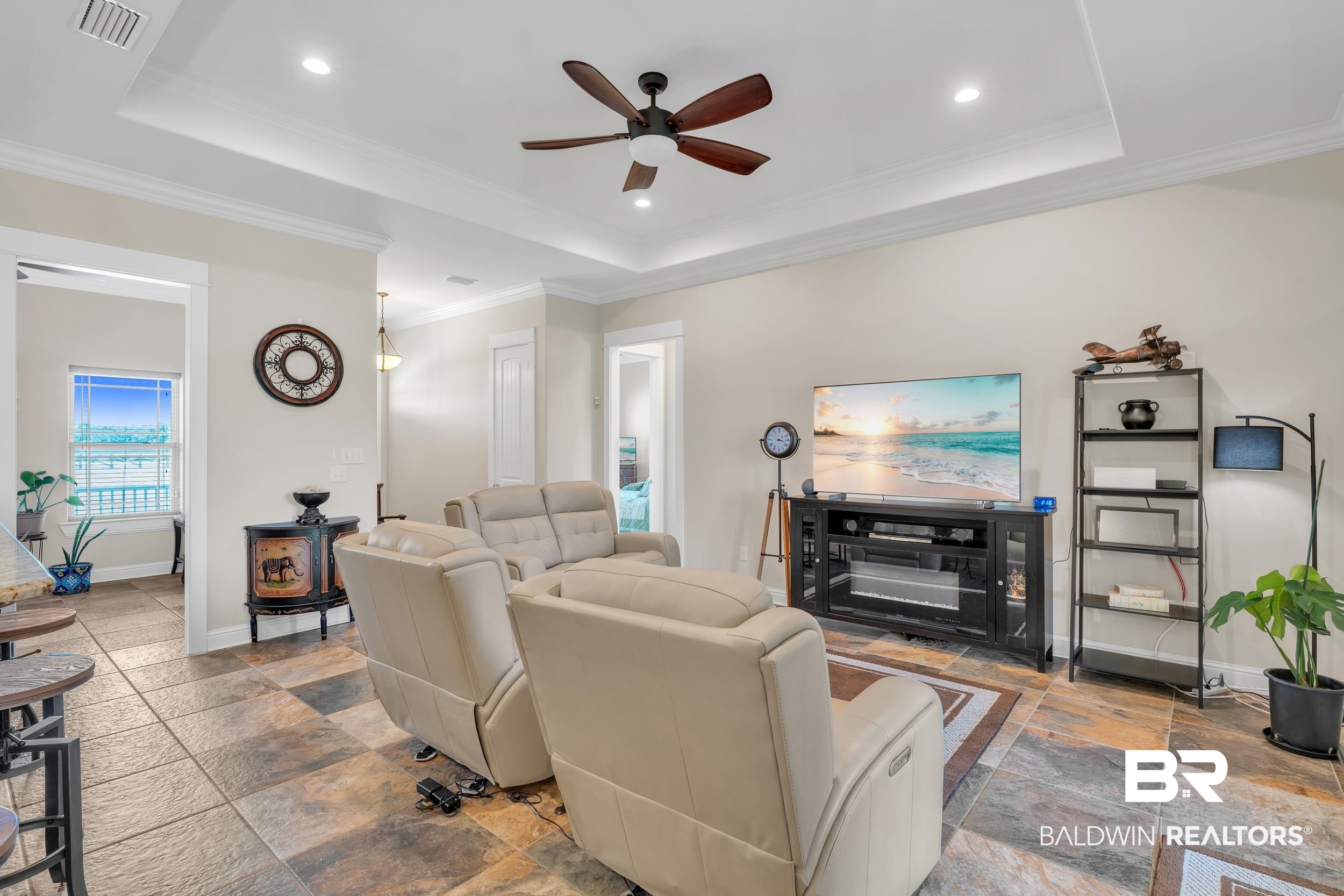 28918 Comstock Road Elberta, AL 36530 - Photo 21 of 53 Living room with a ceiling fan, crown molding, recessed lighting, a tray ceiling, and stone finish floors