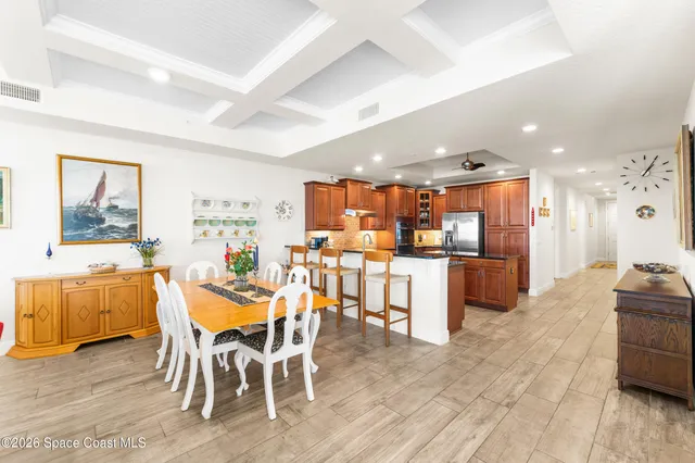 a kitchen with stainless steel appliances granite countertop a refrigerator a sink dishwasher a oven and a dining table with wooden floor