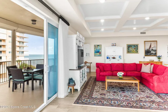 a living room with furniture a rug kitchen view and a large window