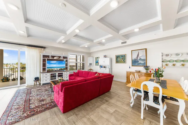 a living room with furniture a rug kitchen view and a large window