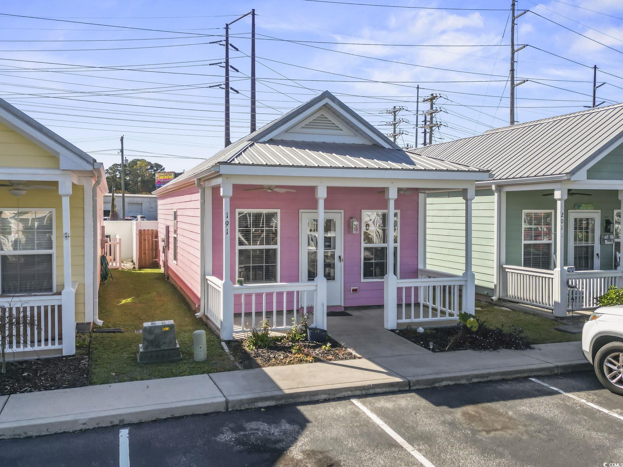 Shotgun-style home featuring a porch, a ceiling fan, uncovered parking, and a metal roof