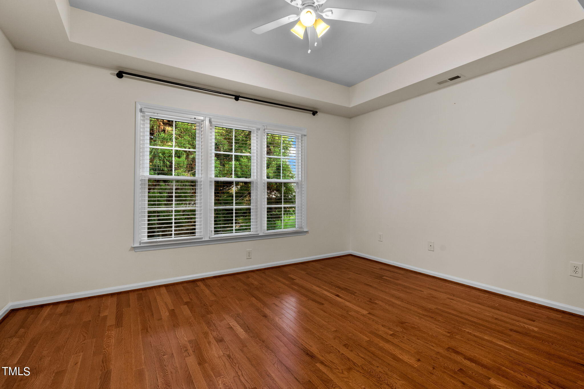8241 Hempshire Place, Unit 102 Raleigh, NC 27613 - Photo 12 of 30 a view of an empty room with wooden floor and a window