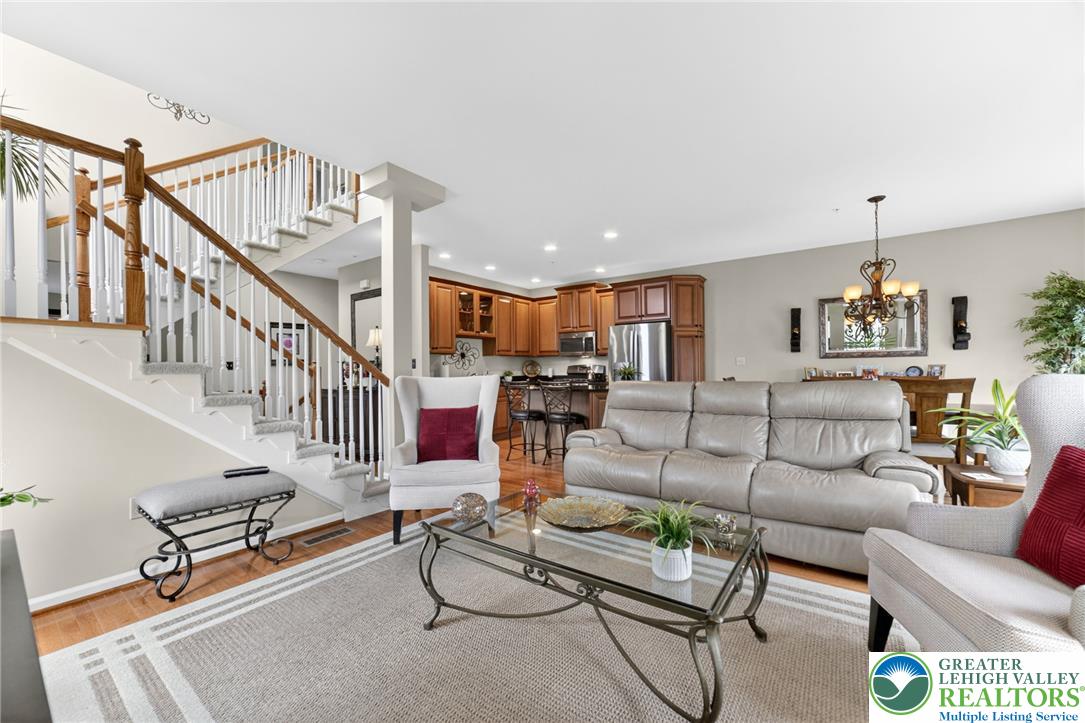 5440 Spring Ridge Drive West Macungie, PA 18062 - Photo 12 of 40 An inviting open-concept living area boasts a modern kitchen and a stately wooden staircase leading to upper levels.