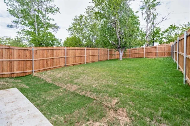 a view of a backyard with a fence and trees