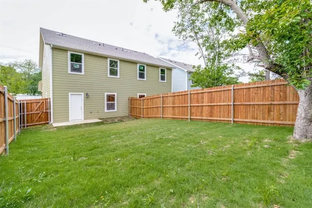 a view of backyard with wooden fence and large trees