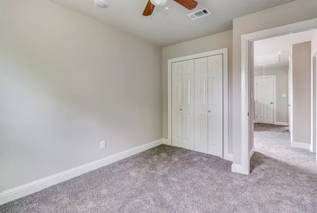 an empty room with a ceiling fan and closet area