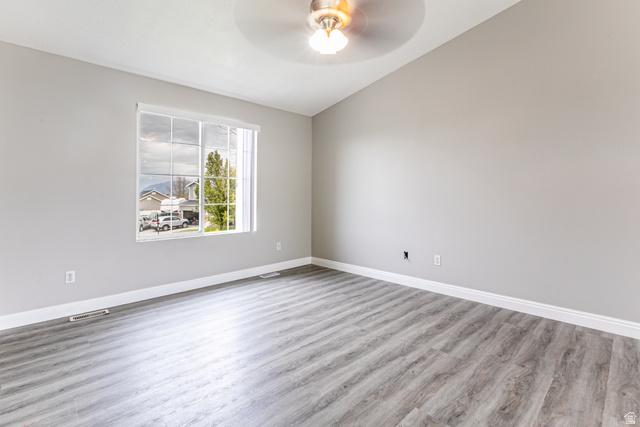 4239 West 5325th Street South Roy, UT 84067 - Photo 5 of 26 Spacious room featuring vaulted ceilings, a ceiling fan with integrated lighting, wood-finish flooring, and a large multi-pane window