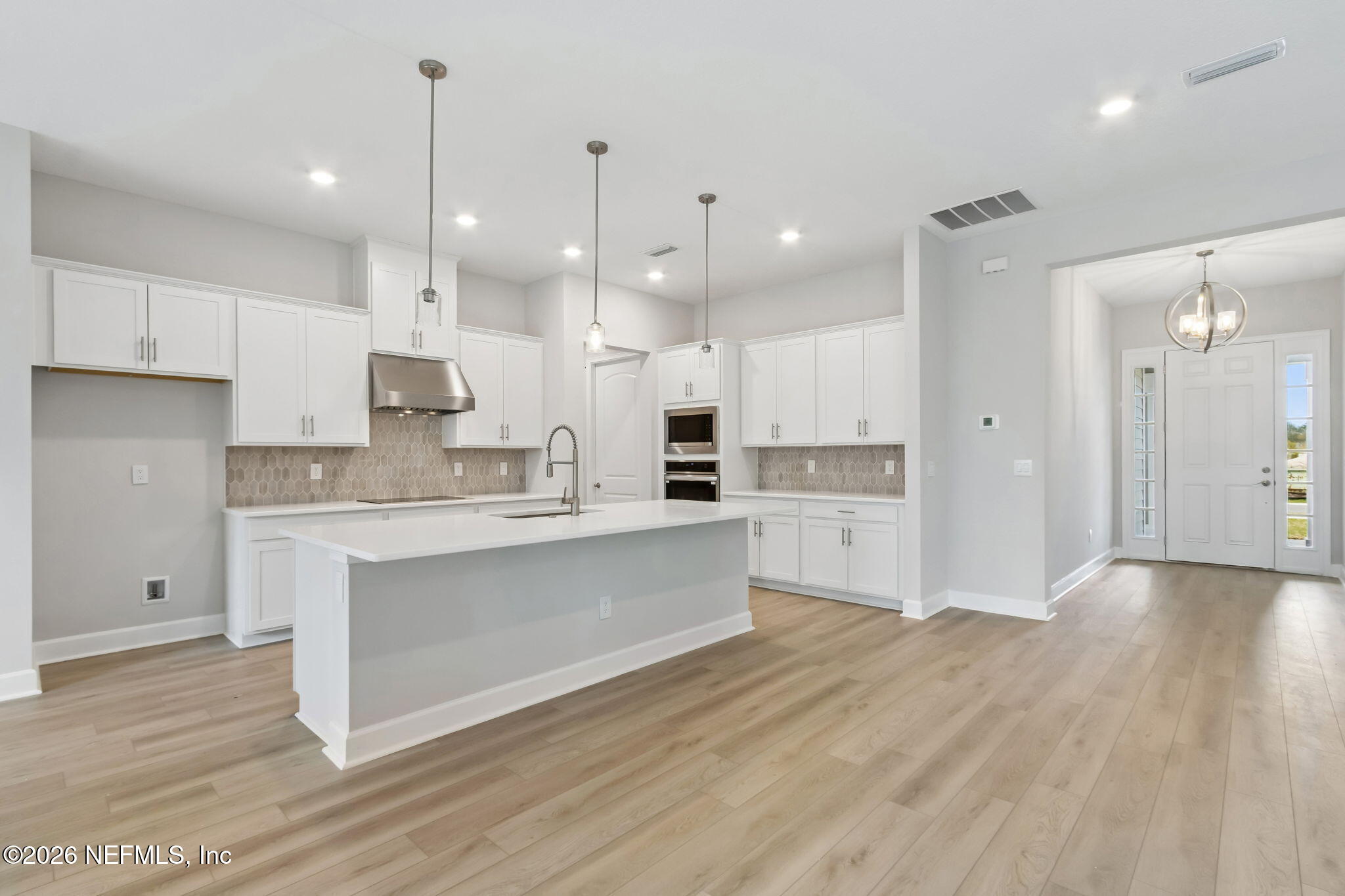 85350 Sandy Rdg Loop, Unit 39 Yulee, FL 32097 - Photo 8 of 29 a large white kitchen with a refrigerator a sink dishwasher a stove and white cabinets with wooden floor