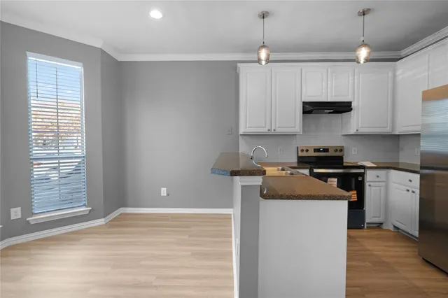 a kitchen with granite countertop a sink cabinets and wooden floor