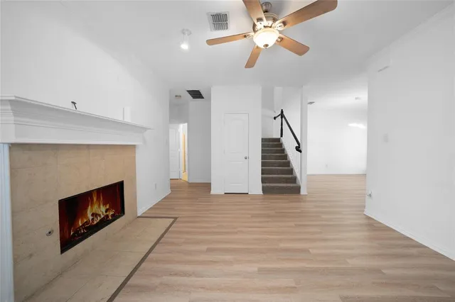 a view of an empty room with wooden floor a fireplace