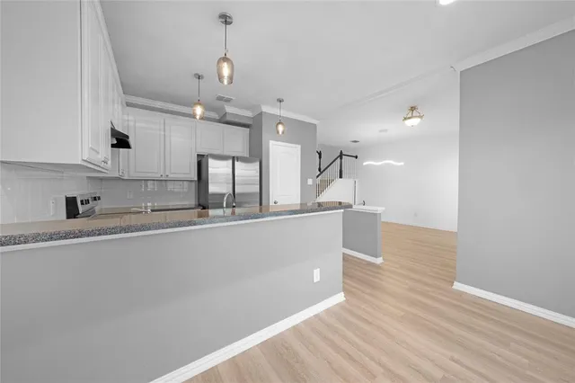 a view of kitchen with granite countertop stainless steel appliances sink and wooden floor