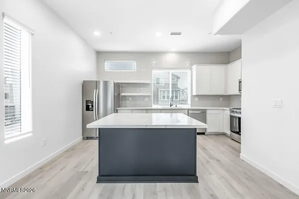 a view with a kitchen island wooden floors and stainless steel appliances