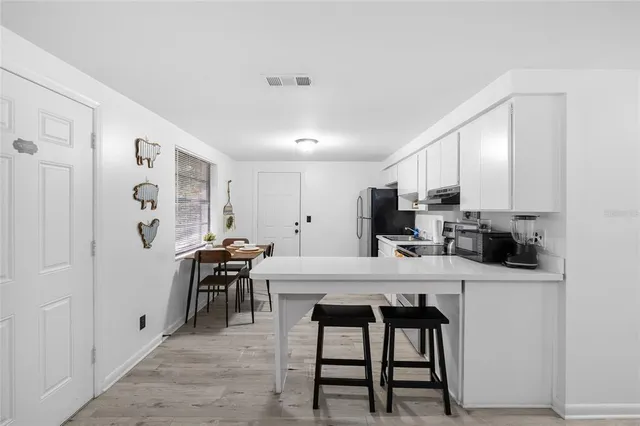 a kitchen with stainless steel appliances a white table chairs and a refrigerator