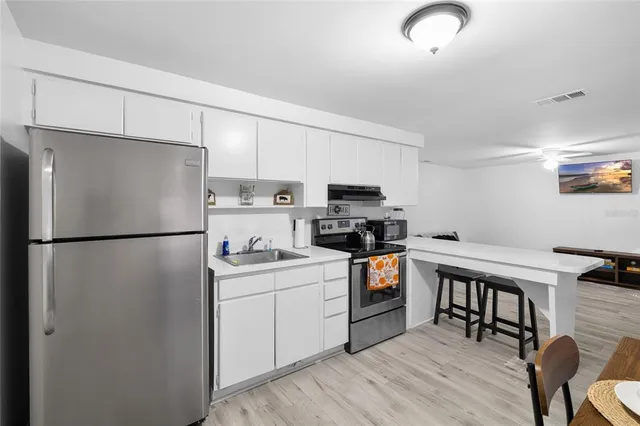 a kitchen with stainless steel appliances a refrigerator a stove a sink a dining table and chairs