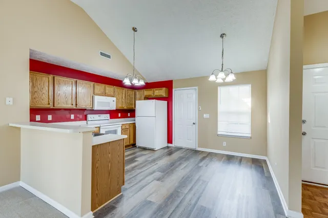 a view of kitchen with stainless steel appliances granite countertop a stove and a wooden floors