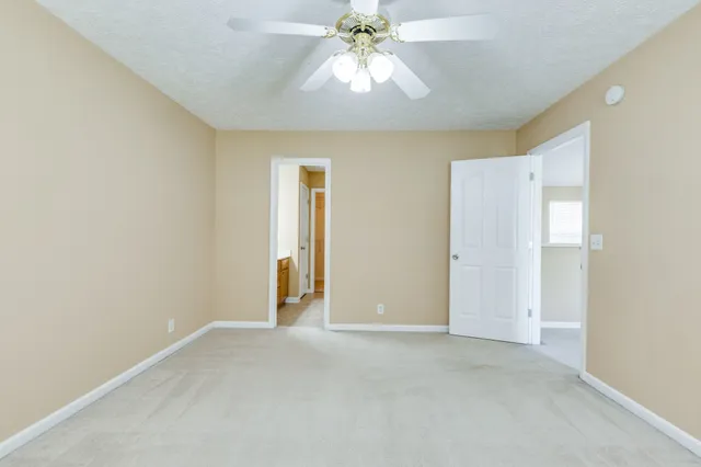 a view of an empty room and chandelier fan