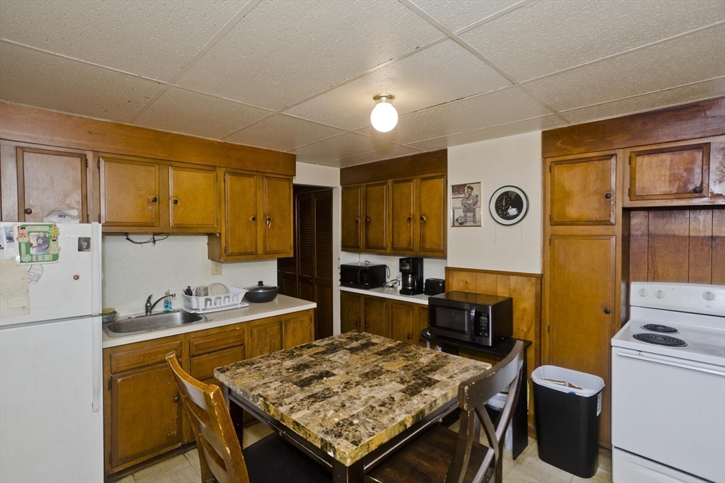 298 Oakland Street Springfield, MA 01108 - Photo 24 of 38 a kitchen with a table chairs and a refrigerator
