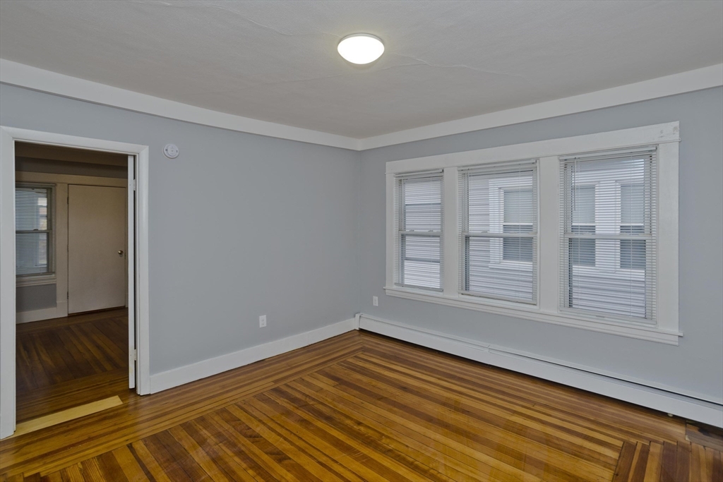 298 Oakland Street Springfield, MA 01108 - Photo 3 of 38 a view of an empty room with wooden floor and a window
