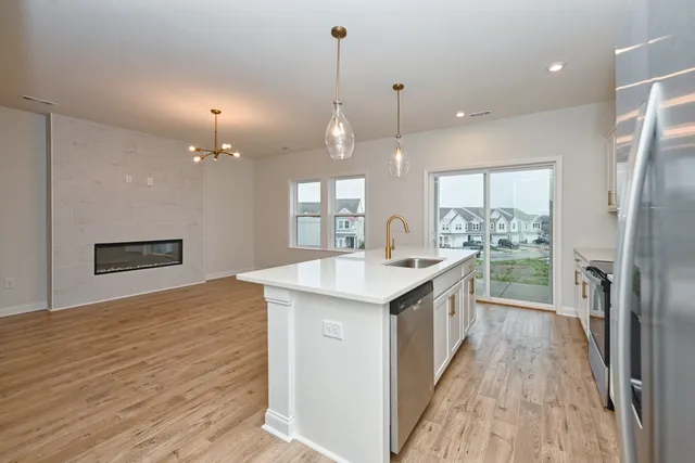 a large kitchen with kitchen island a sink appliances wooden floor and a counter top space
