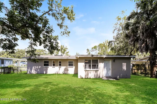a front view of a house with a garden and trees