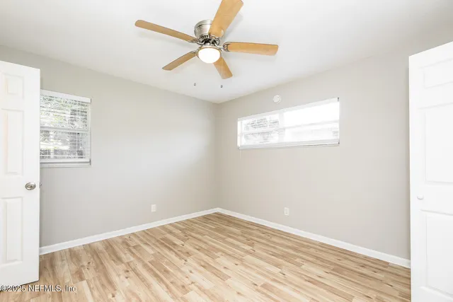 a view of a room with wooden floor and a ceiling fan