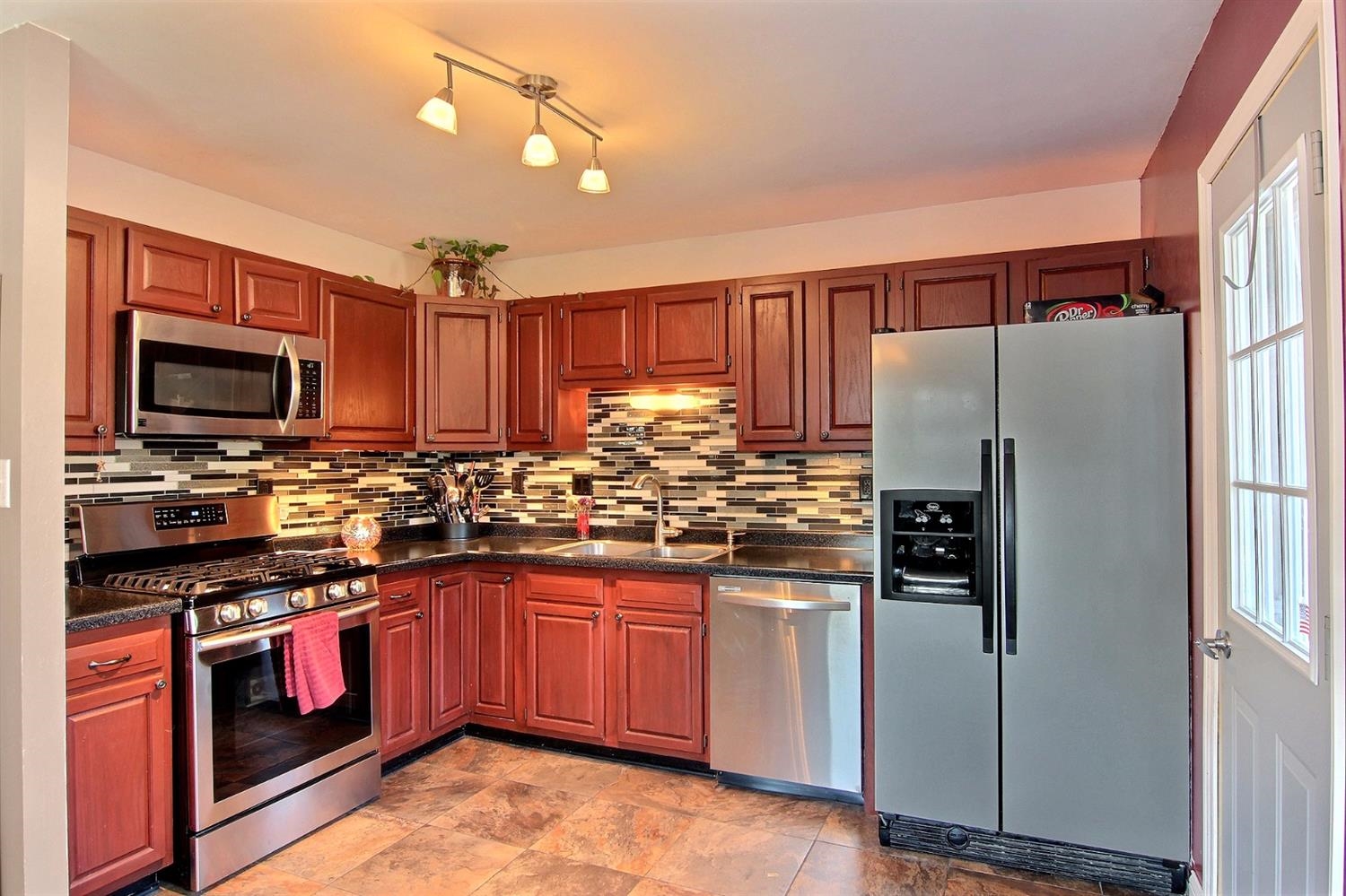 7829 Whitcomb Street Merrillville, IN 46410 - Photo 2 of 10 a kitchen with stainless steel appliances granite countertop a stove top oven a refrigerator and a sink with granite countertops