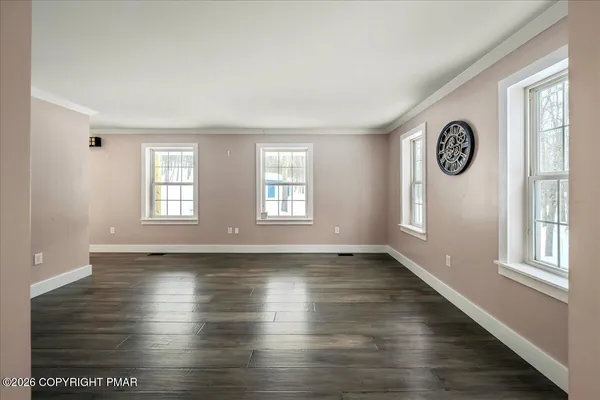 a view of an empty room with a window and wooden floor