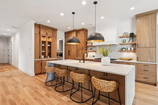 a kitchen with stainless steel appliances granite countertop a sink a stove a refrigerator and island with wooden floor