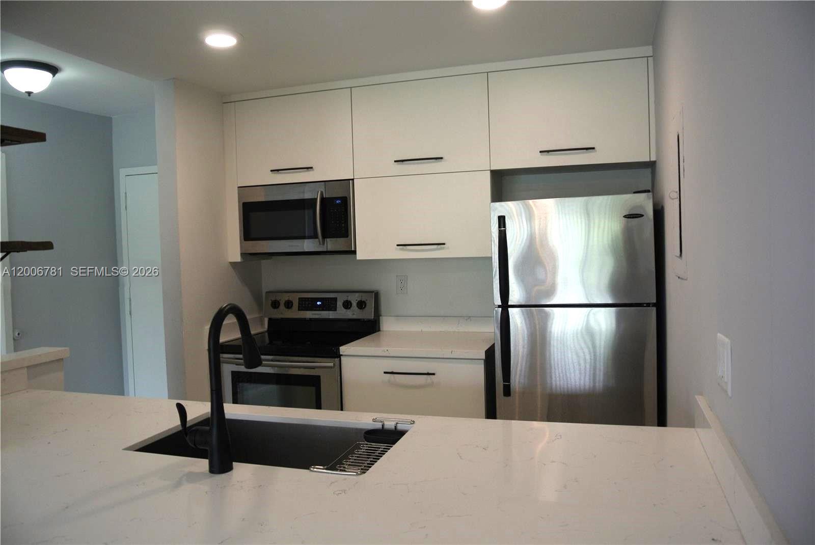 2160 Southwest 16th Avenue, Unit 417 Miami, FL 33145 - Photo 9 of 24 a kitchen with a refrigerator a microwave a stove and cabinets