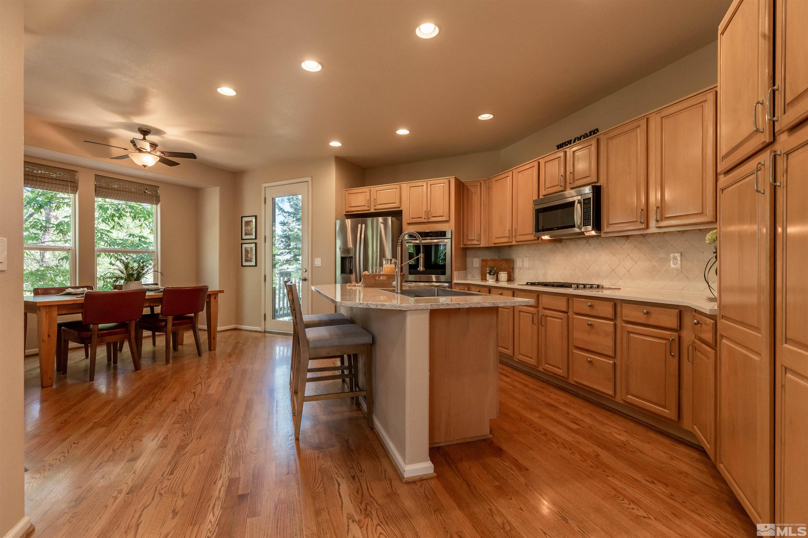 4829 Ramcreek Trail Reno, NV 89519 - Photo 13 of 40 a kitchen with kitchen island granite countertop wooden floors and stainless steel appliances