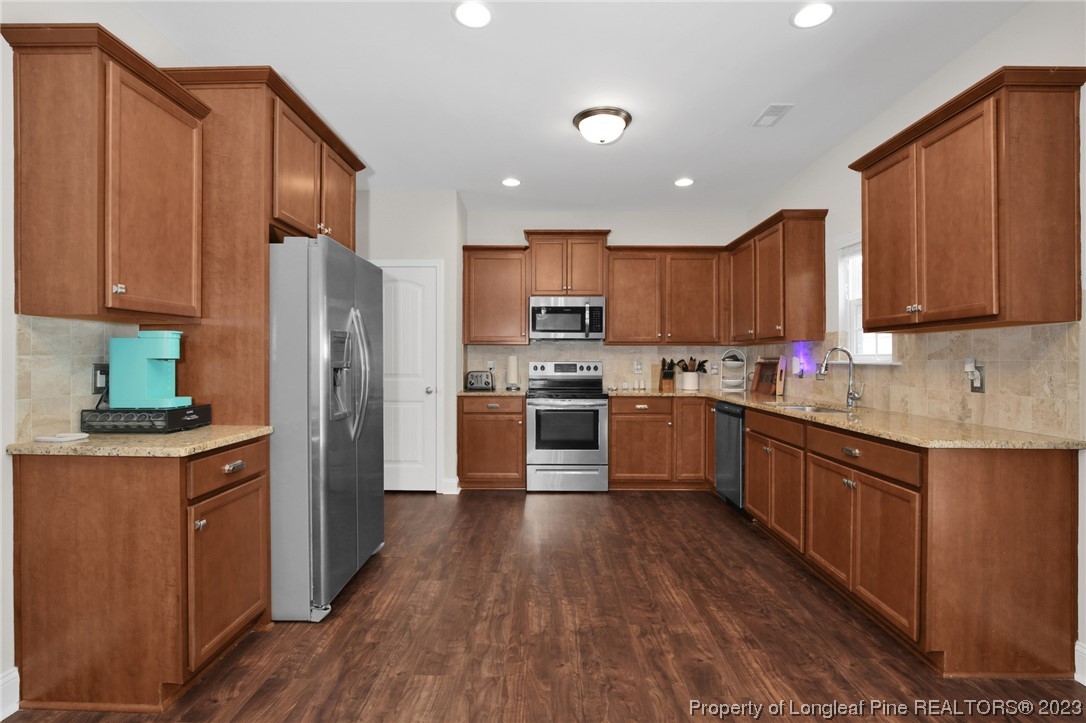 90 Eaker Drive Cameron, NC 28326 - Photo 5 of 36 a kitchen with stainless steel appliances granite countertop a refrigerator a stove top oven a sink and dishwasher with wooden floor