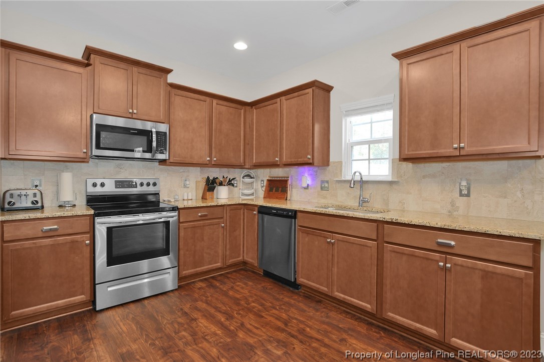 90 Eaker Drive Cameron, NC 28326 - Photo 7 of 36 a kitchen with granite countertop wood cabinets stainless steel appliances and a window