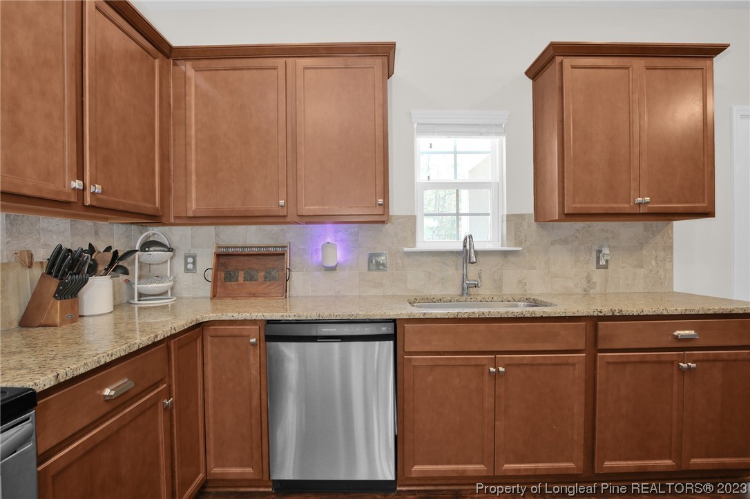 90 Eaker Drive Cameron, NC 28326 - Photo 8 of 36 a kitchen with granite countertop wooden cabinets a sink and dishwasher