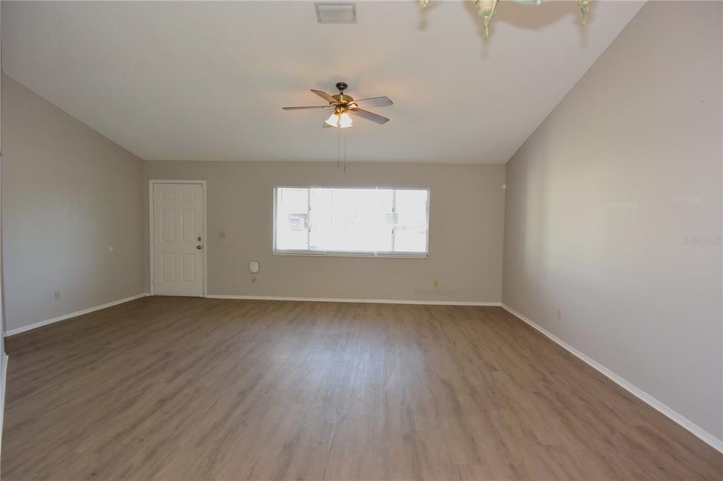 11341 Timbercrest Road Spring Hill, FL 34608 - Photo 5 of 35 an empty room with wooden floor chandelier fan and windows