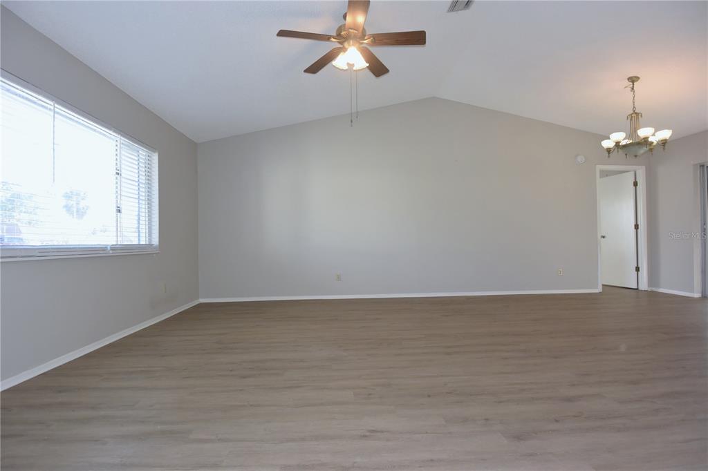 11341 Timbercrest Road Spring Hill, FL 34608 - Photo 8 of 35 an empty room with wooden floor chandelier fan and windows