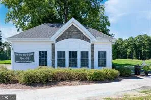 a view of a brick house with a yard plants and large tree