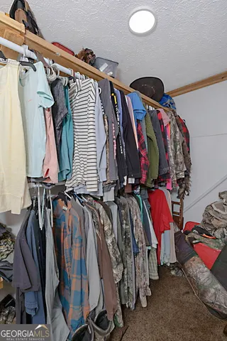 a view of walk in closet with clothes and shoes