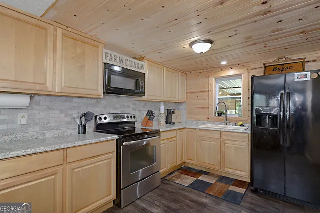 a kitchen with stainless steel appliances granite countertop a stove a sink dishwasher a refrigerator and cabinets with wooden floor