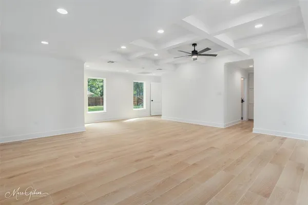 an empty room with wooden floor ceiling fan and windows