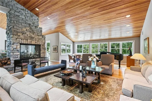 a living room with furniture large windows and wooden floor