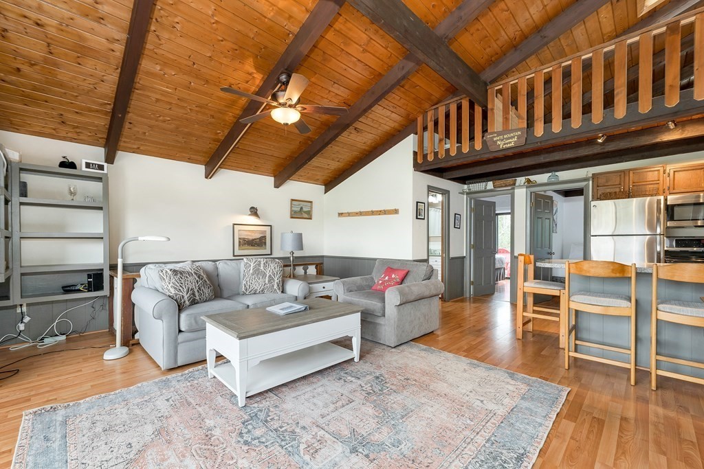 34 Linderhof Golf Course Road, Unit C12 Glen, NH 03838 - Photo 8 of 37 a living room with furniture a wooden floor and a chandelier