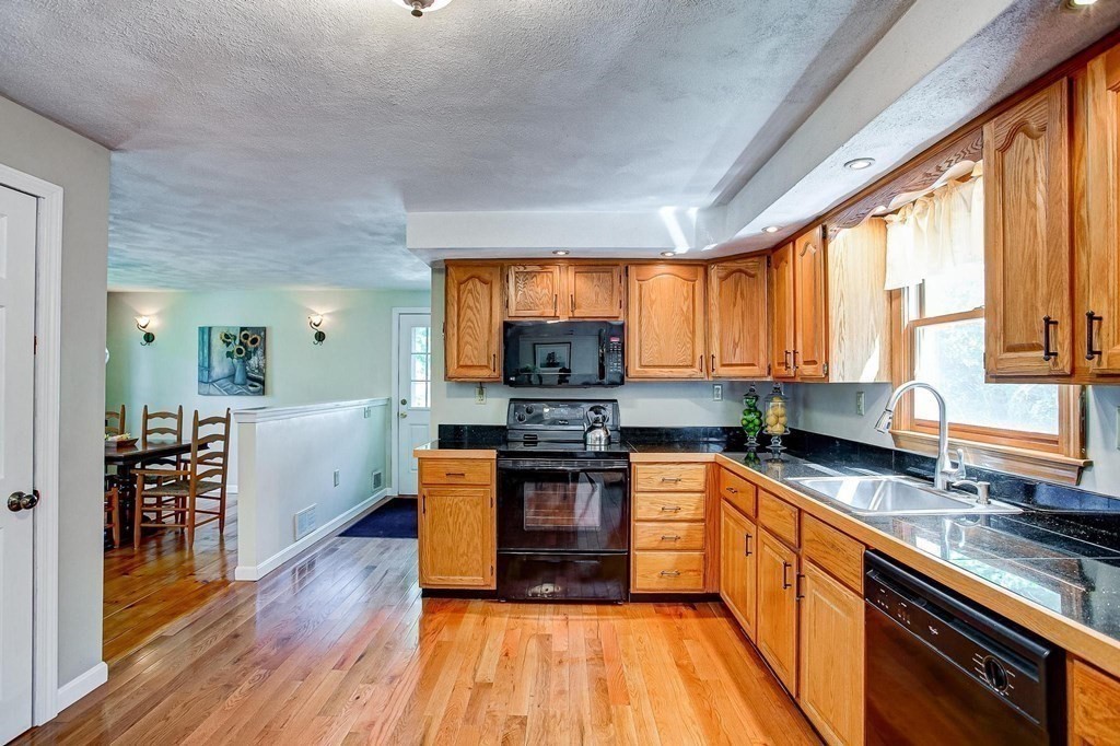 226 Allen Road Billerica, MA 01821 - Photo 9 of 25 a kitchen with stainless steel appliances granite countertop a stove top oven a sink dishwasher a dining table and chairs with wooden floor