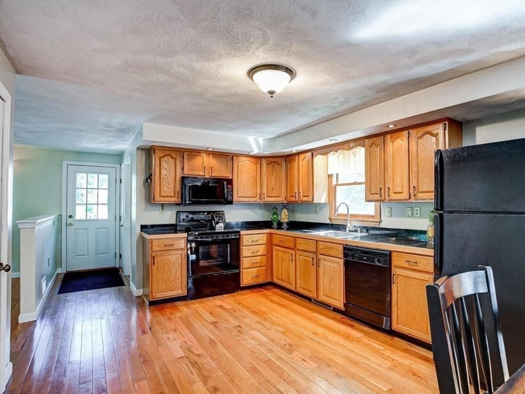 226 Allen Road Billerica, MA 01821 - Photo 10 of 25 a kitchen with stainless steel appliances granite countertop a stove top oven a sink dishwasher a dining table and chairs with wooden floor