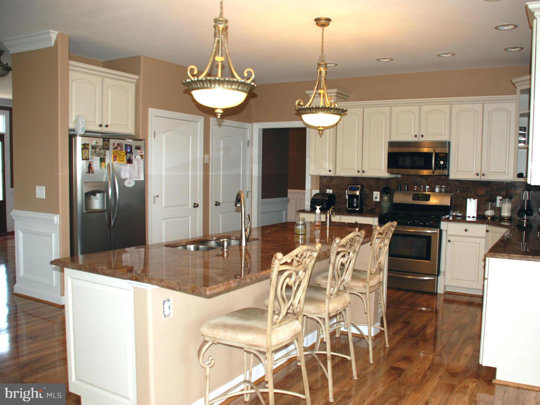 6015 Boston Ridge Court Boston, VA 22713 - Photo 7 of 30 a kitchen with stainless steel appliances granite countertop a stove a refrigerator a sink a dining table and chairs with wooden floor