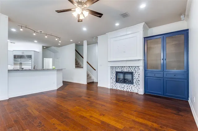 an empty room with wooden floor a kitchen view and a fireplace